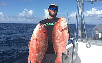Man holding two large red fish
